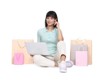 Internet shopping. Happy woman with laptop and colorful bags on white background