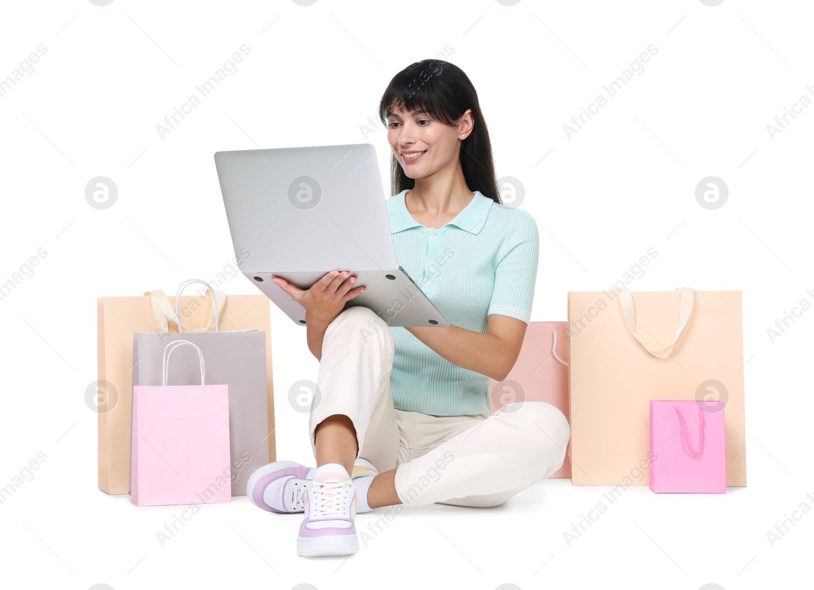 Photo of Internet shopping. Happy woman with laptop and colorful bags on white background