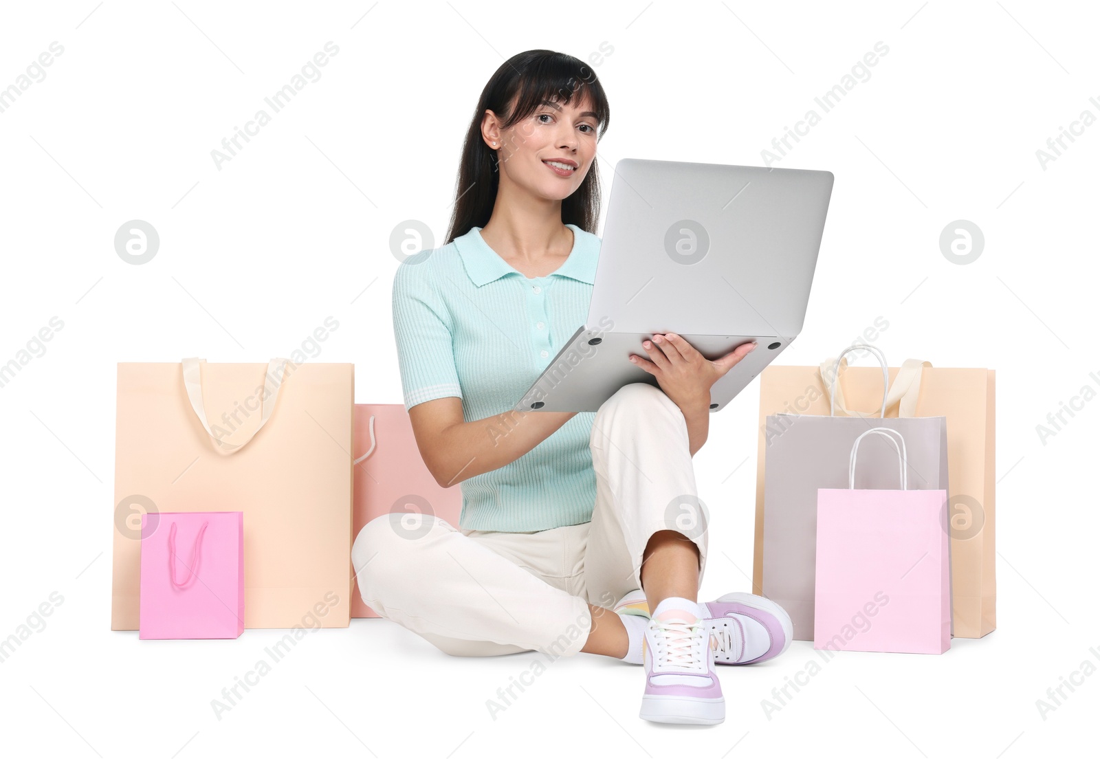 Photo of Internet shopping. Happy woman with laptop and colorful bags on white background