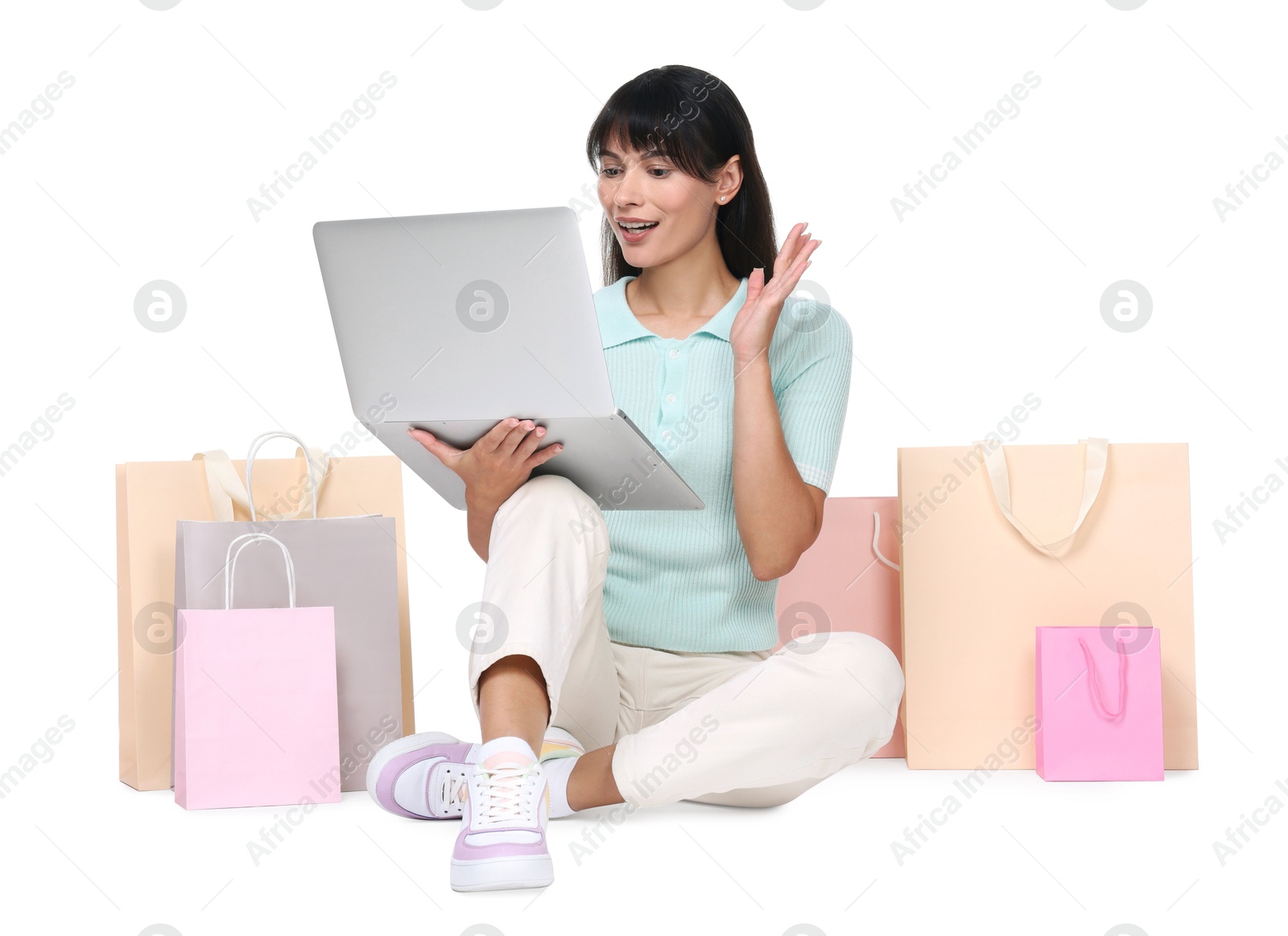 Photo of Internet shopping. Surprised woman with laptop and colorful bags on white background