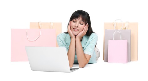 Photo of Internet shopping. Happy woman with laptop and colorful bags on white background