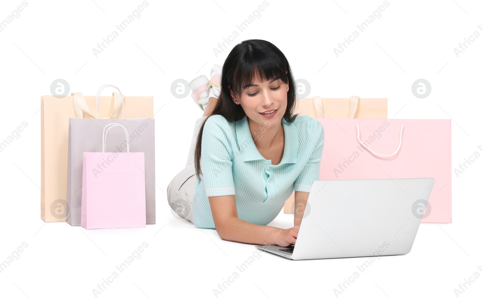 Photo of Internet shopping. Happy woman with laptop and colorful bags on white background