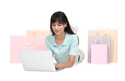 Photo of Internet shopping. Happy woman with laptop and colorful bags on white background