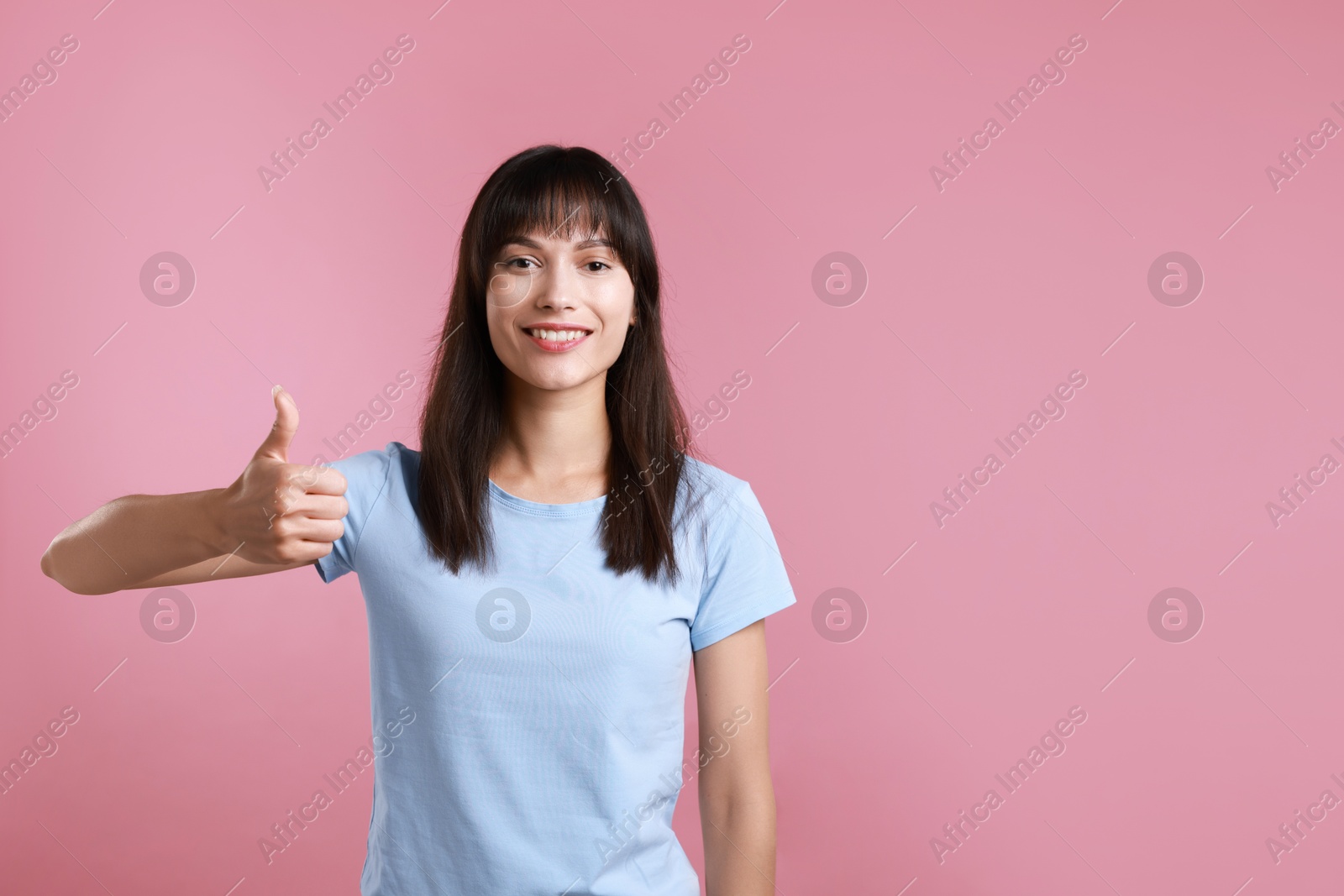 Photo of Happy woman showing thumbs up on pink background, space for text. Like gesture