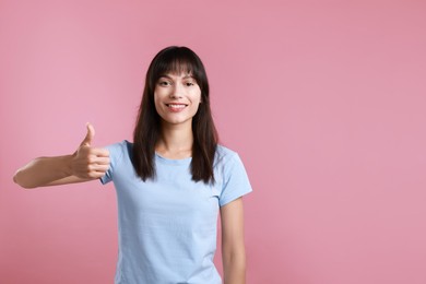 Happy woman showing thumbs up on pink background, space for text. Like gesture