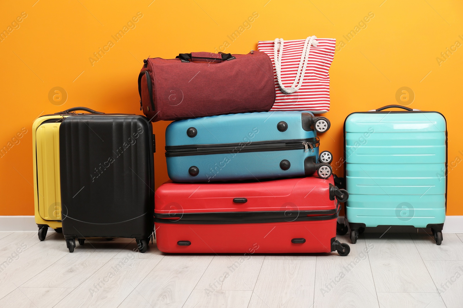 Photo of Many colorful suitcases and bags on floor near orange wall