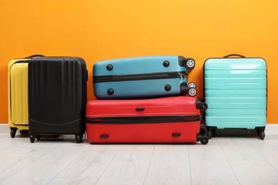 Photo of Many colorful suitcases on floor near orange wall