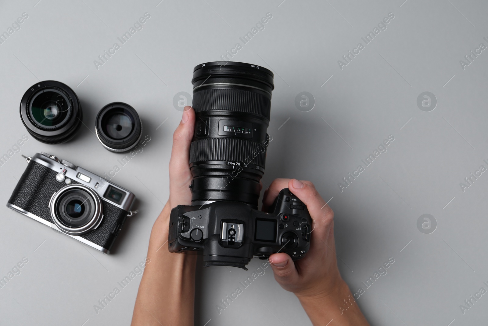 Photo of Photographer with professional camera on grey background, top view