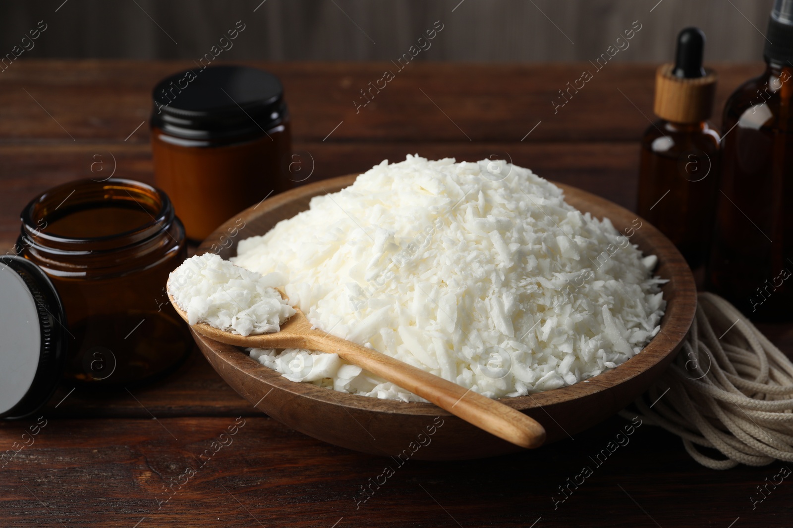 Photo of Soy wax and other supplies for making candles on wooden table, closeup