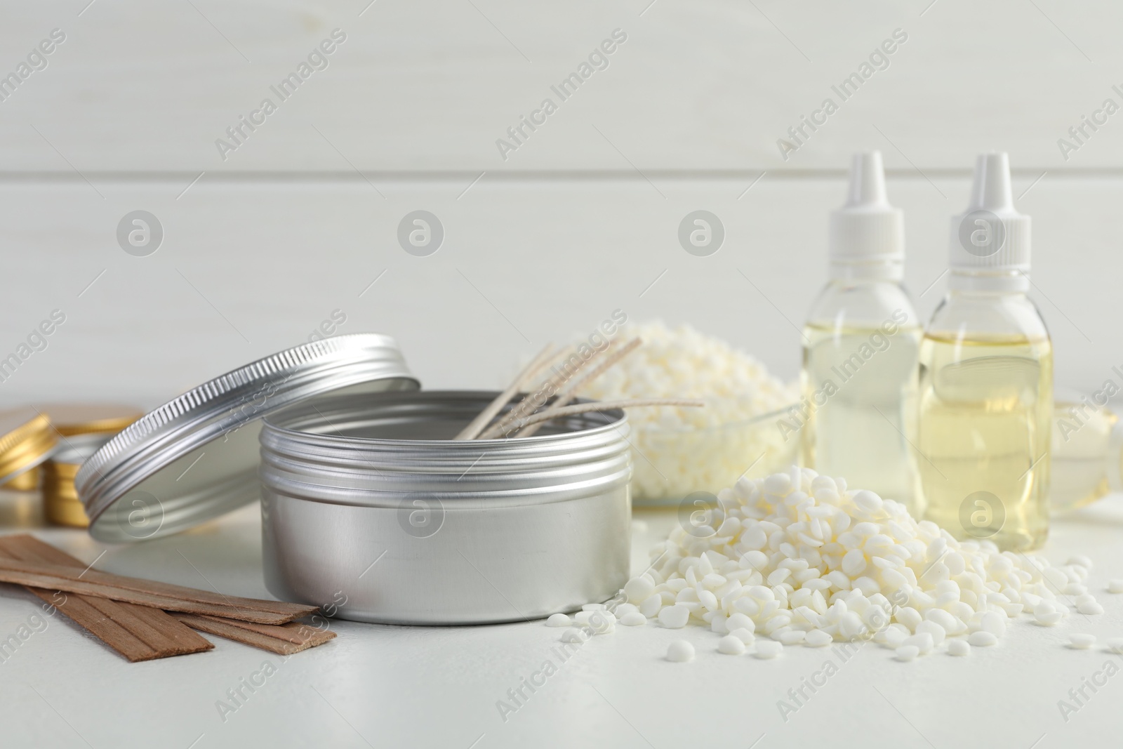 Photo of Soy wax and other supplies for making candles on white table, closeup