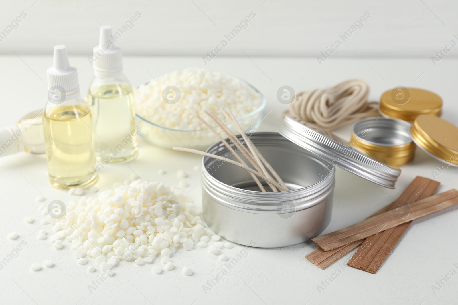 Photo of Soy wax and other supplies for making candles on white table, closeup