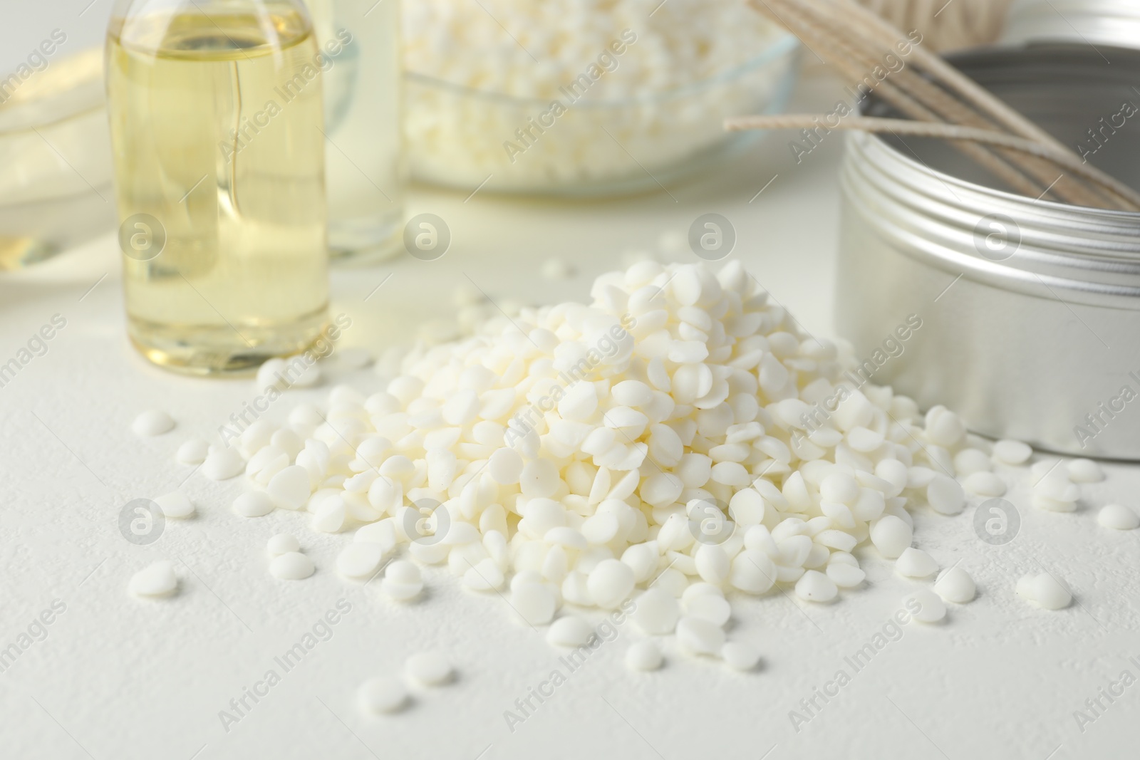 Photo of Soy wax and scented oil on white table, closeup. Candle making