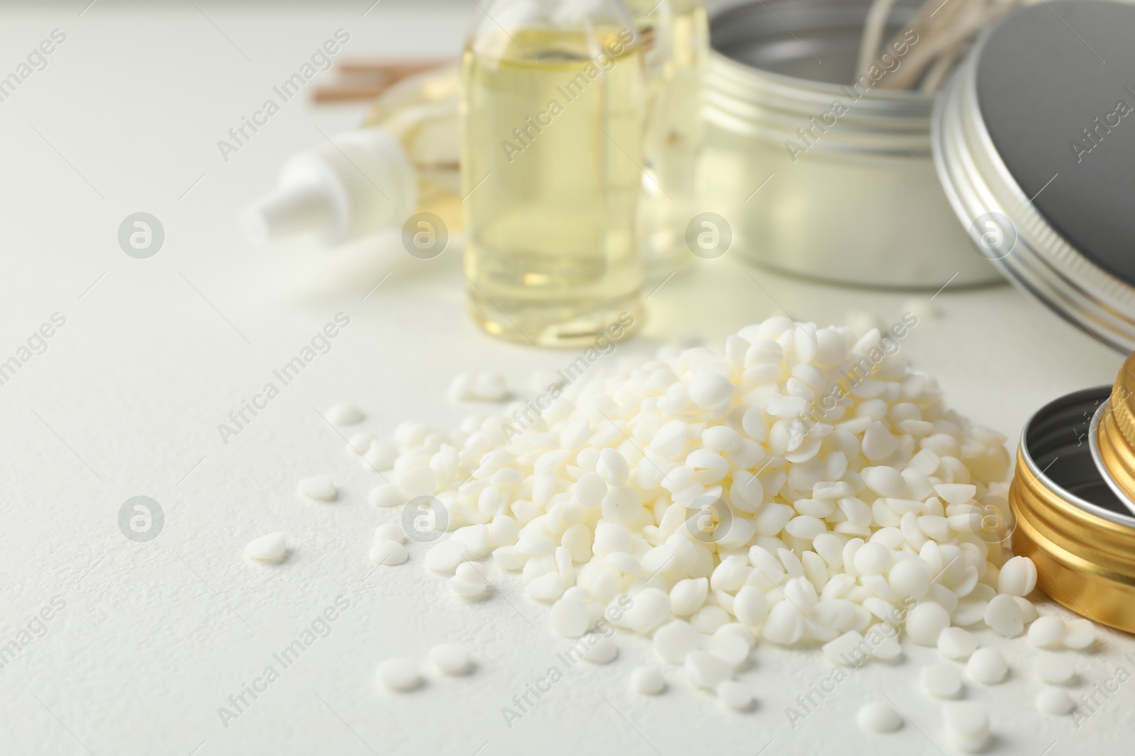 Photo of Soy wax and other supplies for making candles on white table, closeup