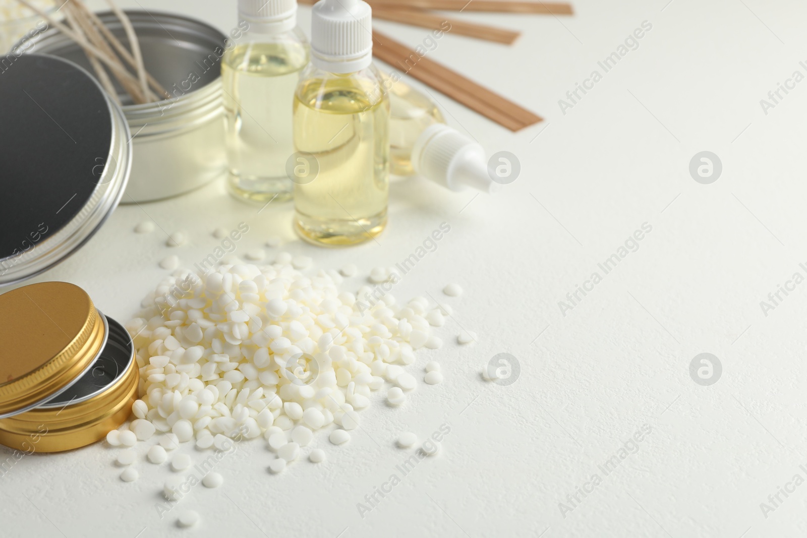 Photo of Soy wax and other supplies for making candles on white table. Space for text