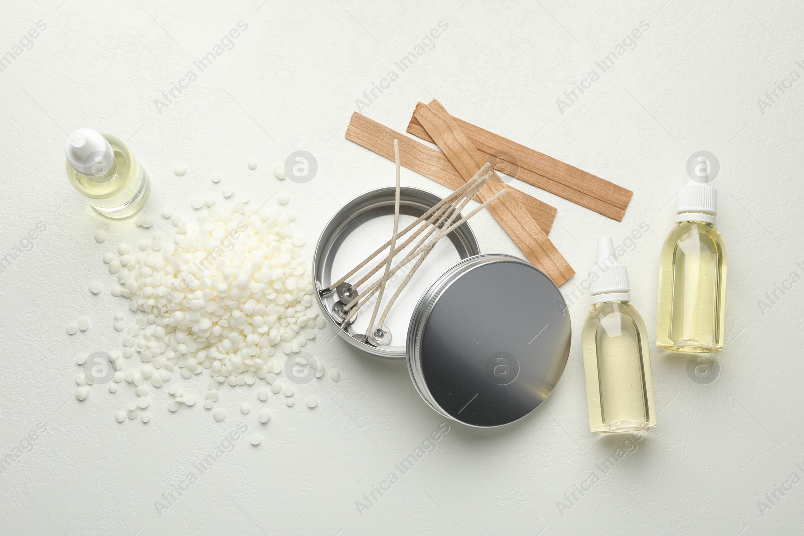 Photo of Soy wax and other supplies for making candles on white table, flat lay