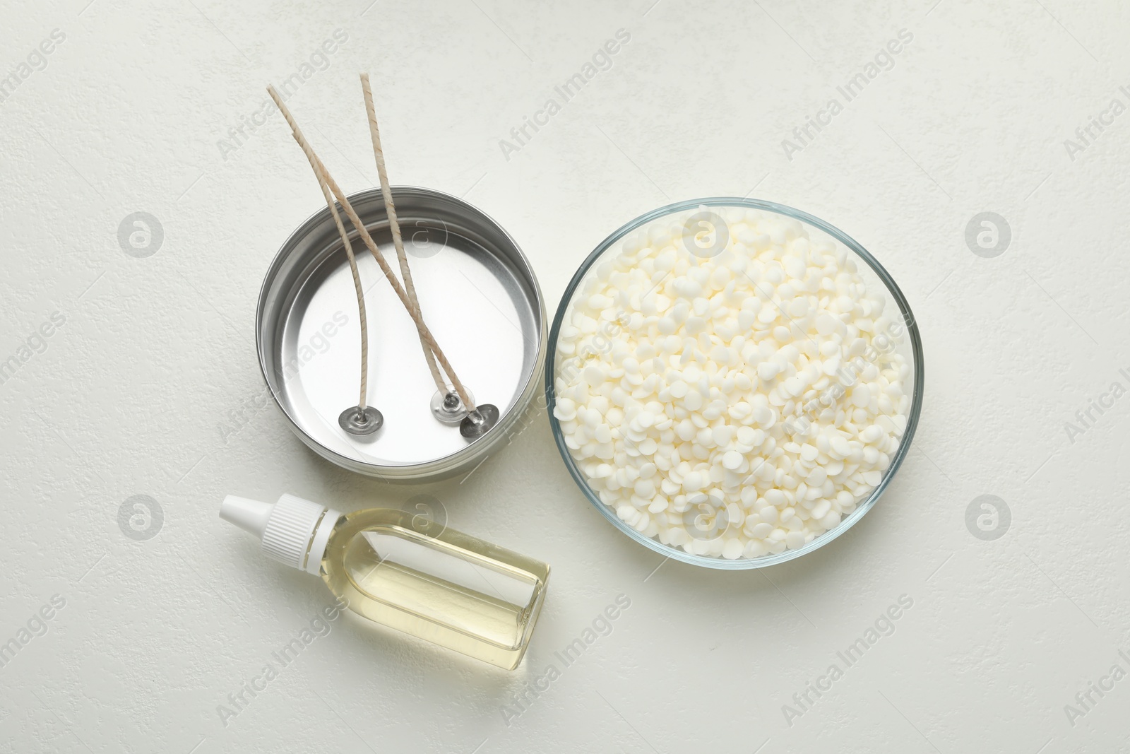 Photo of Soy wax, candle wicks and scented oil on white background, top view