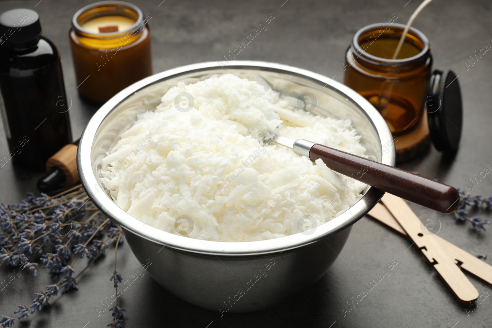 Photo of Soy wax and other supplies for making candles on grey table, closeup