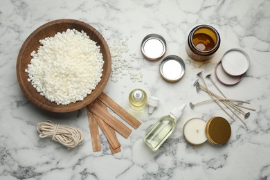 Photo of Soy wax and other supplies for making candles on white marble table, flat lay