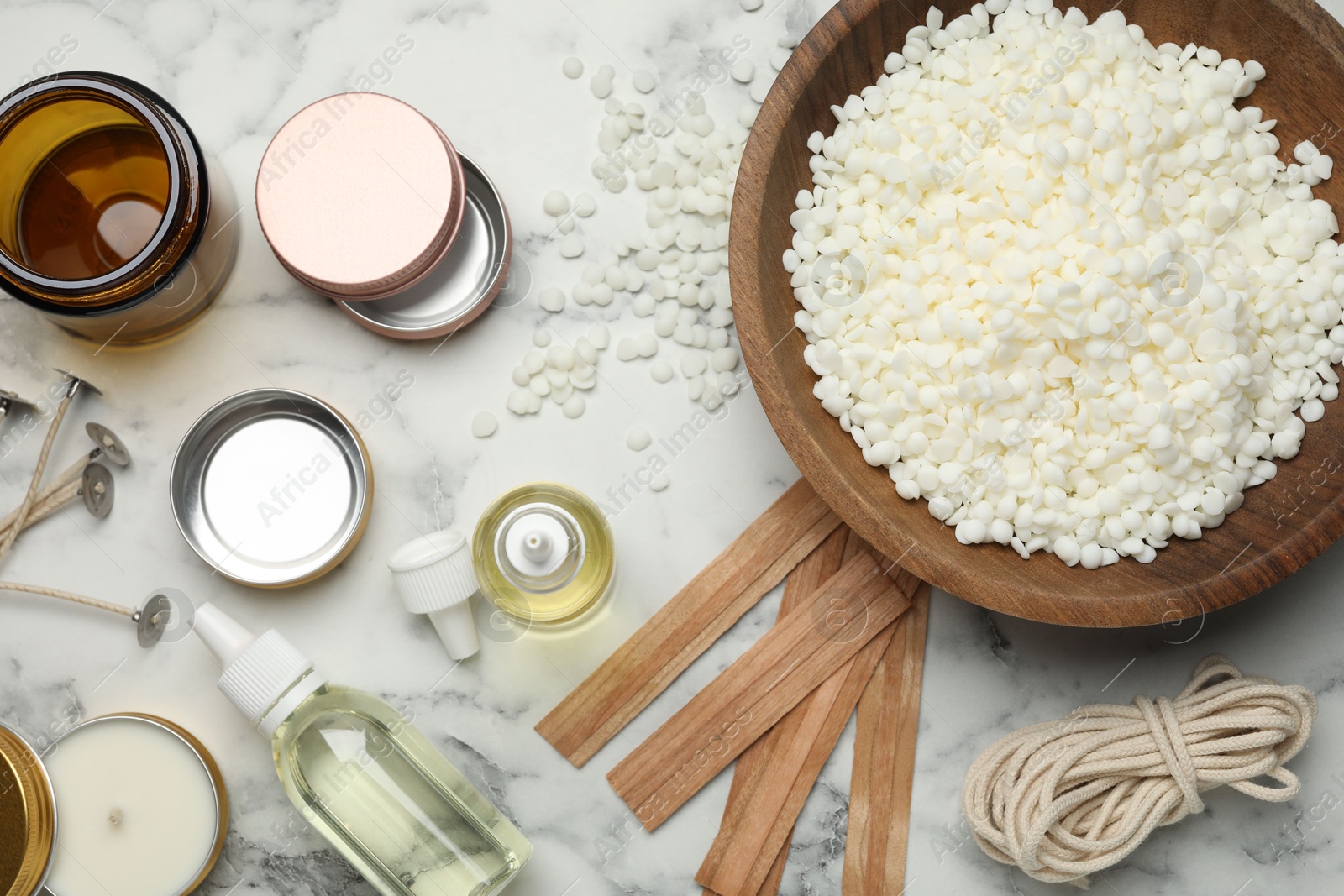 Photo of Soy wax and other supplies for making candles on white marble table, flat lay