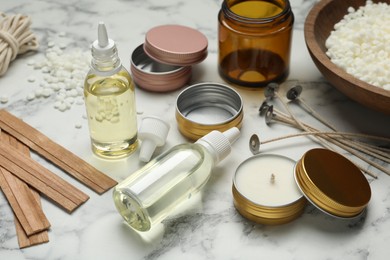 Photo of Soy wax and other supplies for making candles on white marble table, closeup