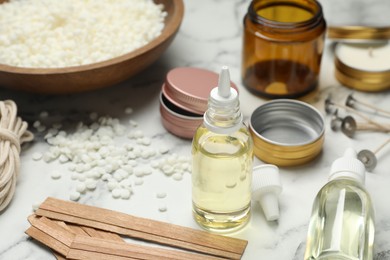 Photo of Soy wax and other supplies for making candles on white marble table, closeup