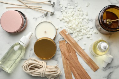 Photo of Soy wax and other supplies for making candles on white marble table, flat lay