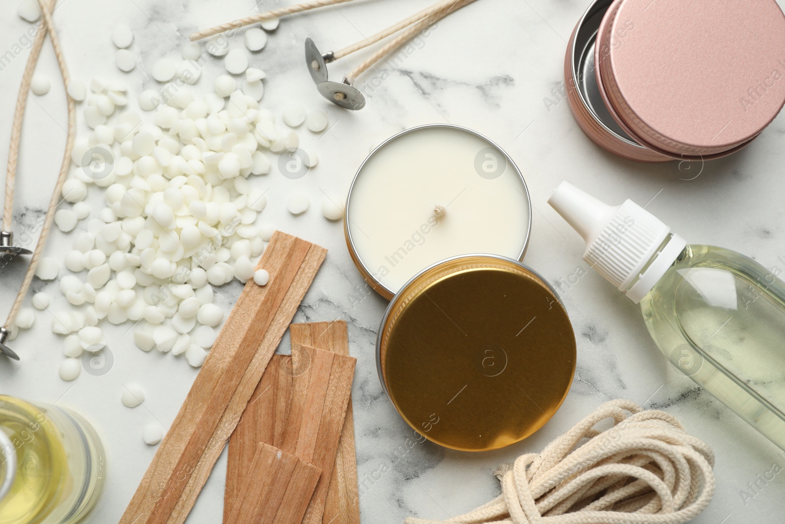 Photo of Soy wax and other supplies for making candles on white marble table, flat lay