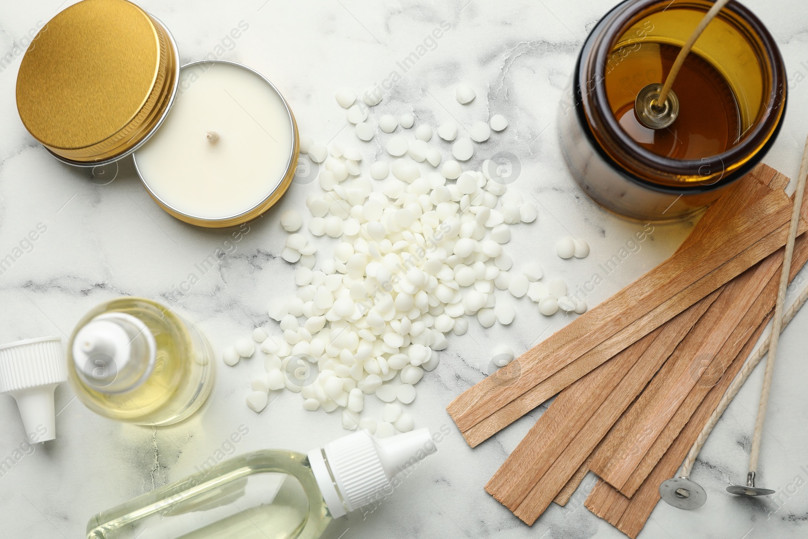 Photo of Soy wax and other supplies for making candles on white marble table, flat lay