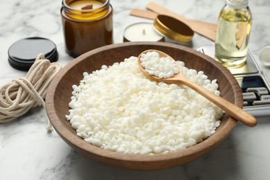 Photo of Soy wax and other supplies for making candles on white marble table, closeup