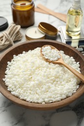 Photo of Soy wax and other supplies for making candles on white marble table, closeup