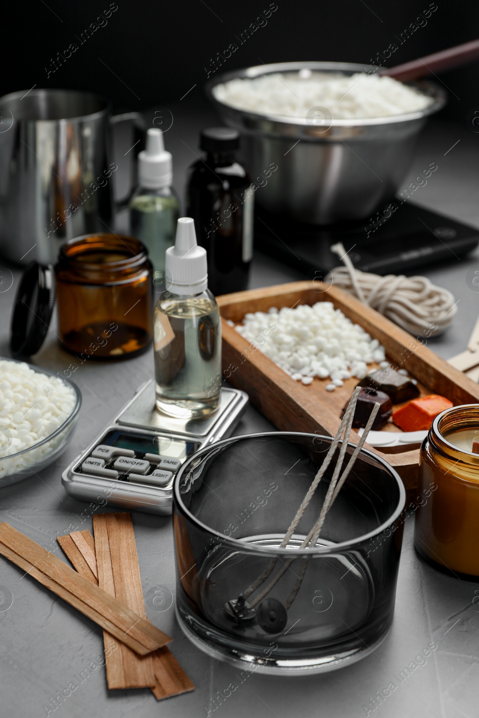 Photo of Soy wax, essential oils and different tools for making candles on gray table, selective focus