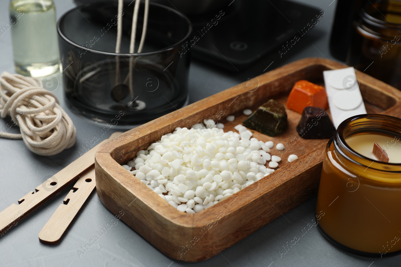 Photo of Soy wax and different tools for making candles on gray table, closeup