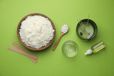 Photo of Making homemade candles. Soy wax in bowl, jars with stabilizers, wicks and essential oil on green background, flat lay