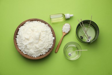 Photo of Making homemade candles. Soy wax in bowl, jars with stabilizers, wicks and essential oil on green background, flat lay