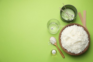 Photo of Making homemade candles. Soy wax in bowl, jars with stabilizers, wicks and essential oil on green background, flat lay. Space for text