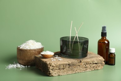 Photo of Soy wax, essential oils, different tools for making candles and piece of wood on green background