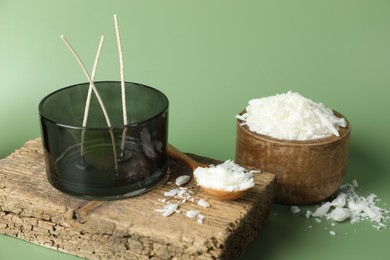 Photo of Making homemade candles. Soy wax, jar with wicks and spoon on green background