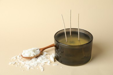 Photo of Soy wax, candle and spoon on beige background, space for text