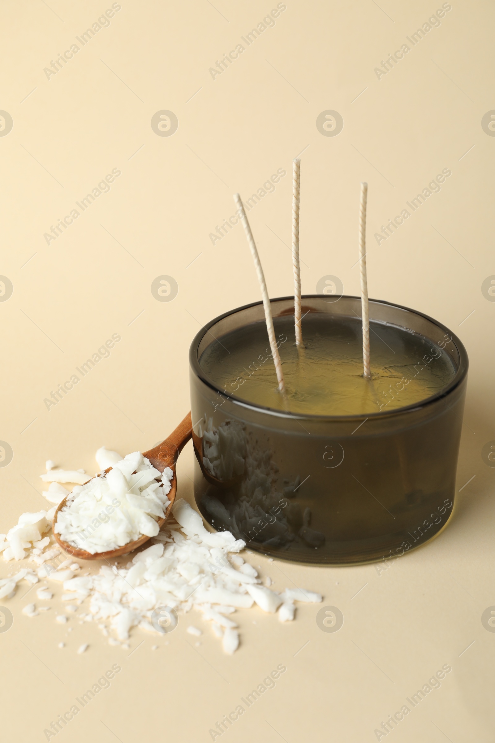 Photo of Soy wax, candle and spoon on beige background