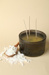 Photo of Soy wax, candle and spoon on beige background