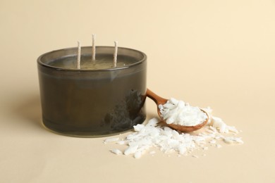 Photo of Soy wax, candle and spoon on beige background