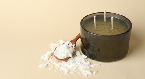 Photo of Soy wax, candle and spoon on beige background, closeup. Space for text