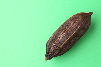 Photo of Cocoa pod on green background, top view. Space for text