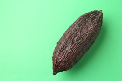 Cocoa pod on green background, top view. Space for text