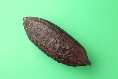 Photo of Cocoa pod on green background, top view