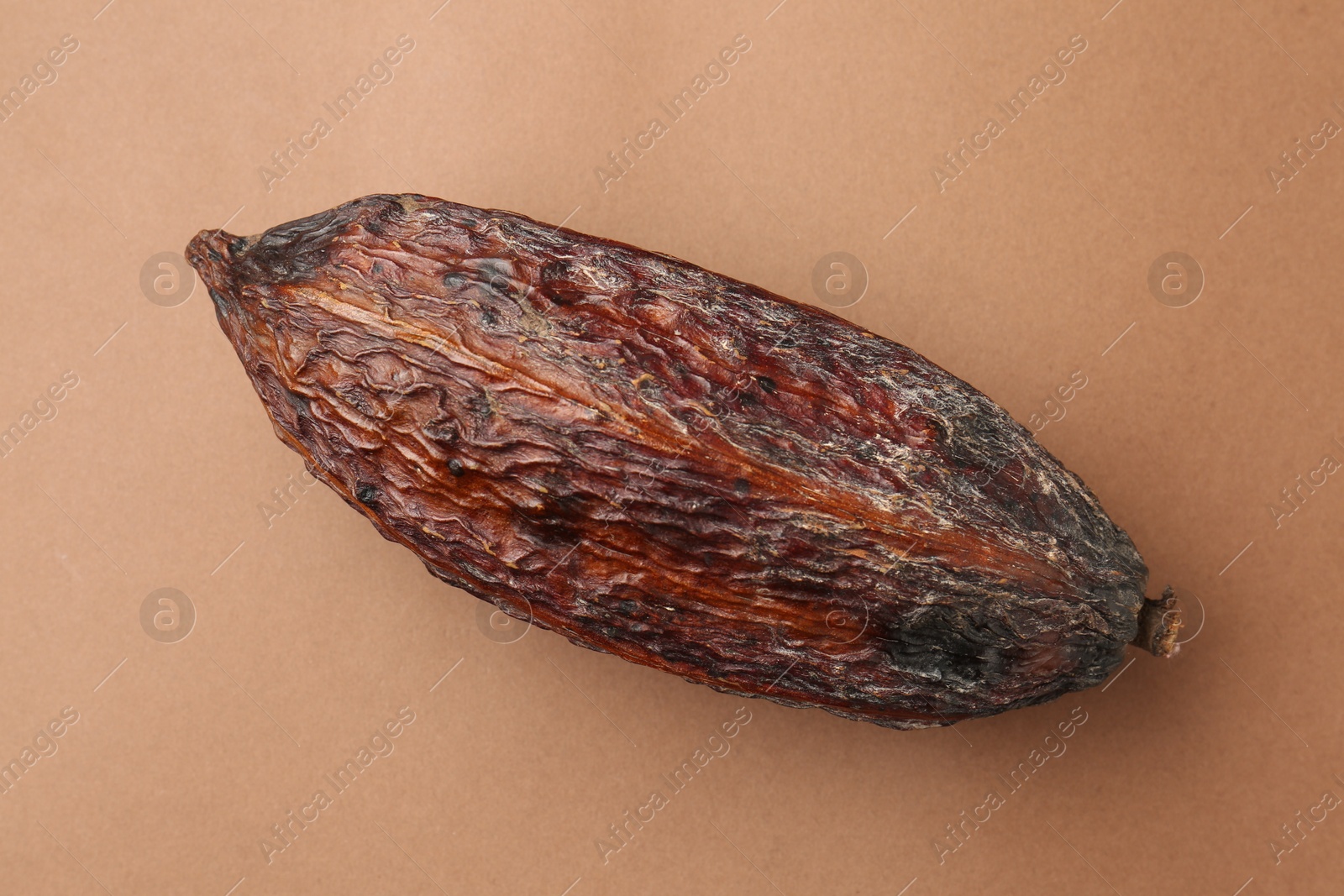 Photo of Cocoa pod on brown background, top view