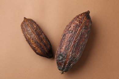 Cocoa pods on brown background, top view