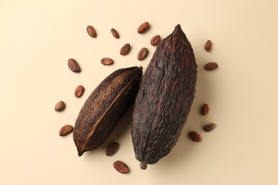 Cocoa pods and beans on beige background, flat lay