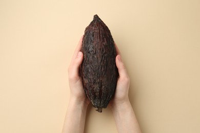 Photo of Woman with cocoa pod on beige background, top view