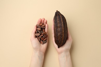 Woman with cocoa pod and beans on beige background, top view